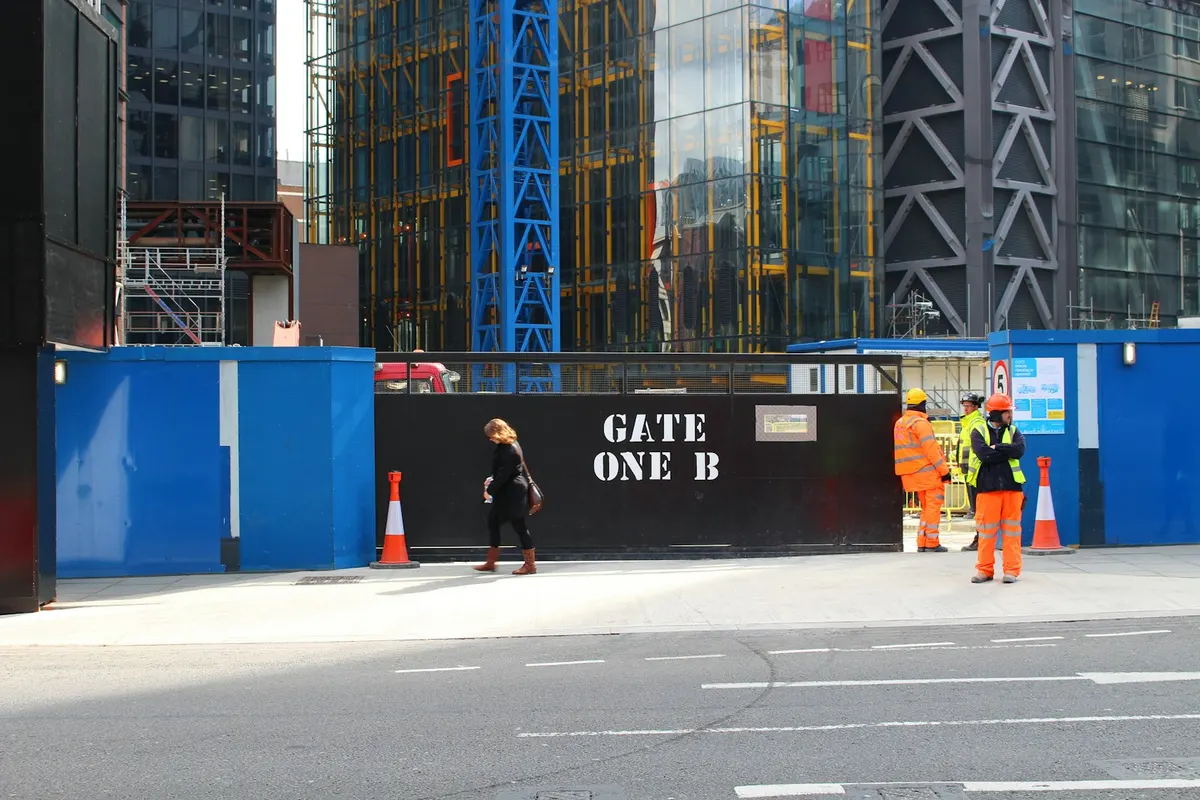 Workers in hi-vis at a construction site gate